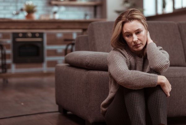Girl sitting in front of couch looking depressed